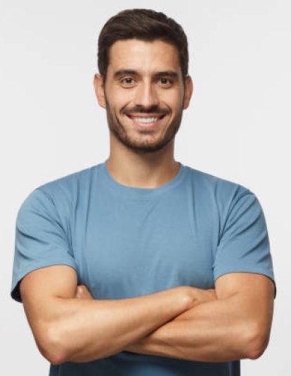 Portrait of smiling handsome man in blue t-shirt standing with crossed arms isolated on grey background